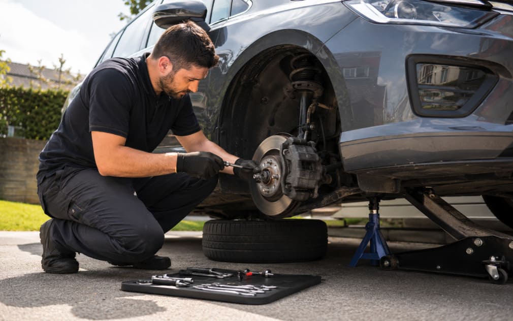Mobile mechanic inspecting brake pads and rotor on a vehicle at the customer’s location